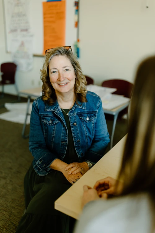 A professor meeting with a student in the classroom.